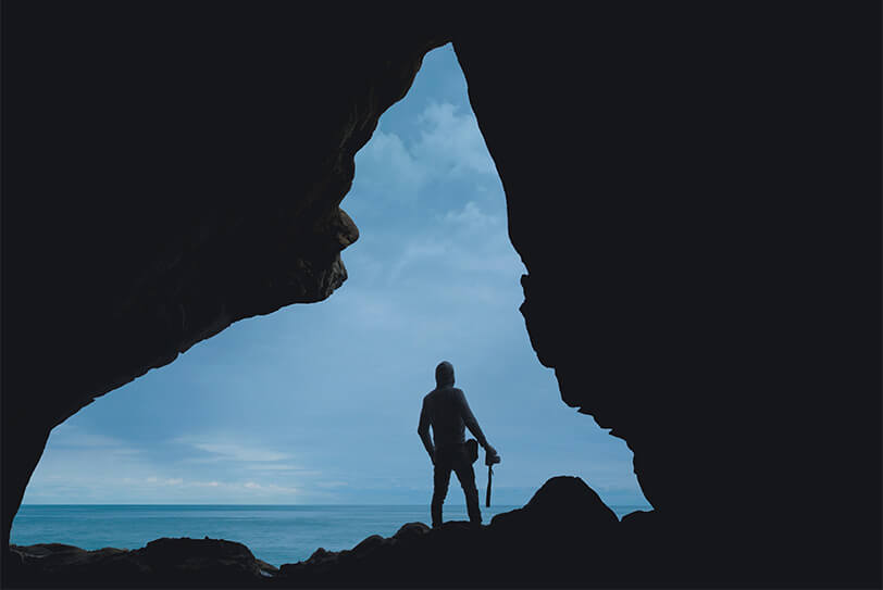 Un photographe regardant l'horizon à l'entrée d'une grotte